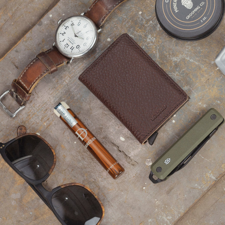 Men's everyday carry essentials — wallet, pocket knife, belt, and sunglasses