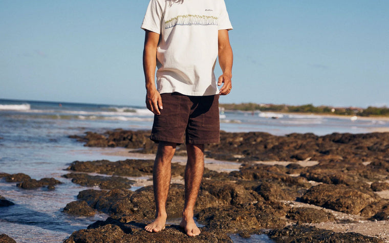 A man in Katin cord shorts on the beach — men's summer shorts styled with a tee