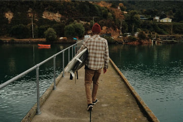 man walking with a surfboard at a dock