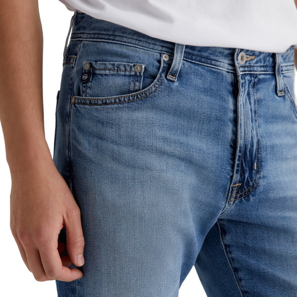 Close-up of denim texture, stitching, and waistband label on the AG Jeans Everett in Prolific