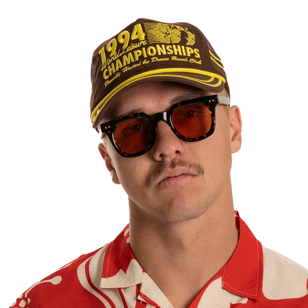 Person wearing the Duvin 94 Hat in Brown in a casual, sun-soaked setting