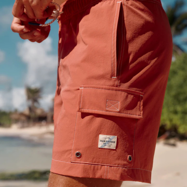 Person wearing the Fair Harbor Breaker Short in Washed Red at the beach or poolside in a casual summer setting