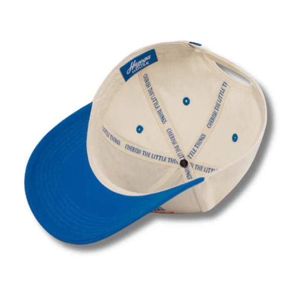 Flat lay of Huega House Moments Hat in Blue/Natural highlighting the embroidered “Moments” text, natural brim, and structured blue crown