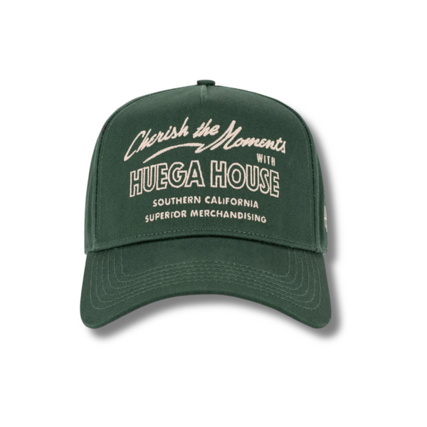 Front view of Huega House Moments Hat in Pine Green featuring clean “Moments” embroidery on a structured crown with a matching curved brim