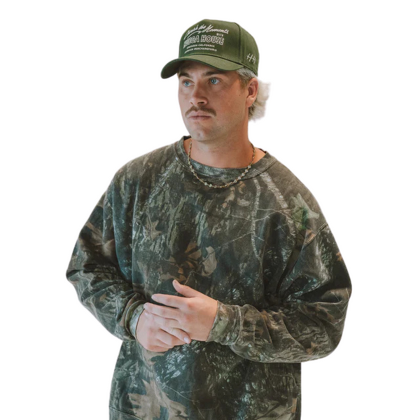 Person wearing the Huega House Moments Hat in Pine Green in a relaxed outdoor or casual everyday setting