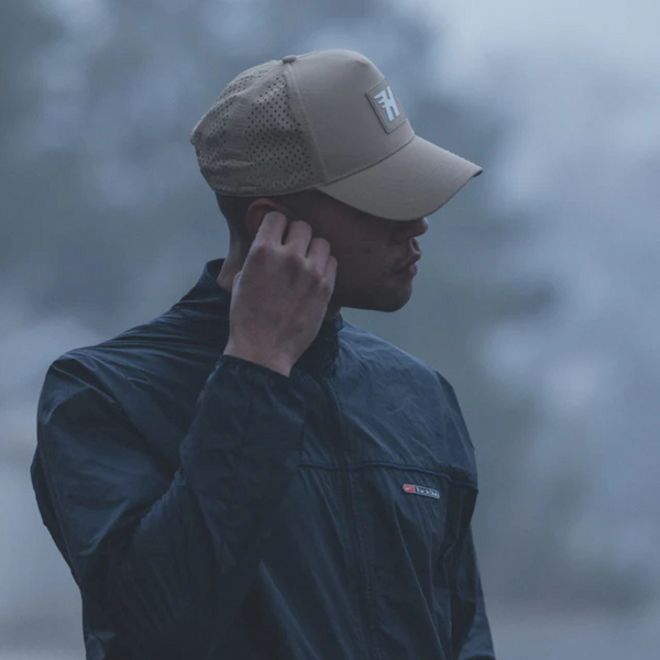 Person wearing the Huega House Success Performance Hat in Khaki in an outdoor, active, or travel-ready setting