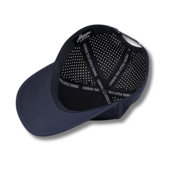 Flat lay of Huega House Performance Hat – Success in Navy showing tonal stitching, moisture-wicking fabric, and front logo detail