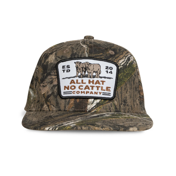 Front view of Sendero All Hat No Cattle Hat in Mossy Oak featuring a structured crown, curved brim, and bold embroidered "All Hat No Cattle" patch